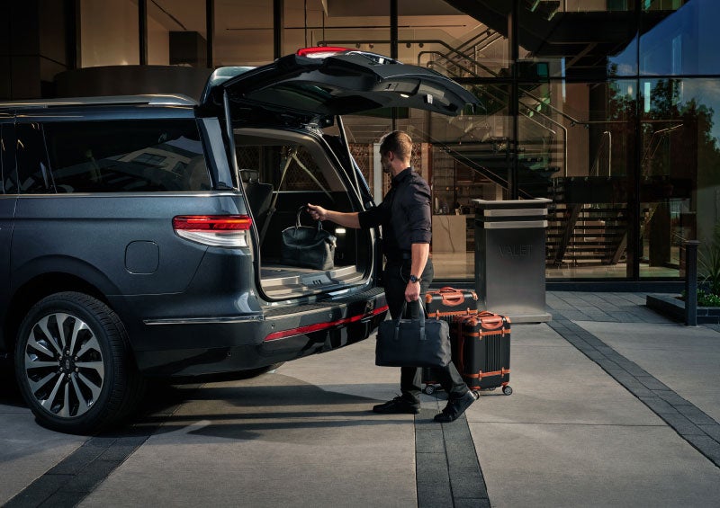 A valet is unloading luggage from the rear cargo area of a 2024 Lincoln Navigator® SUV.