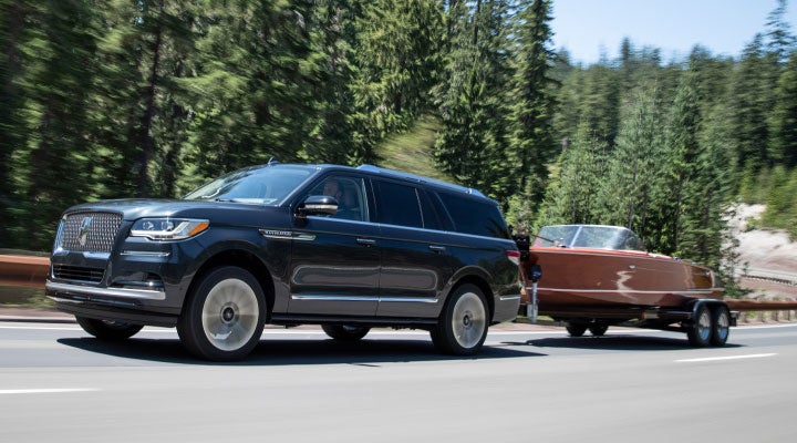 A 2024 Lincoln Navigator® SUV with standard four-wheel drive tows a boat.