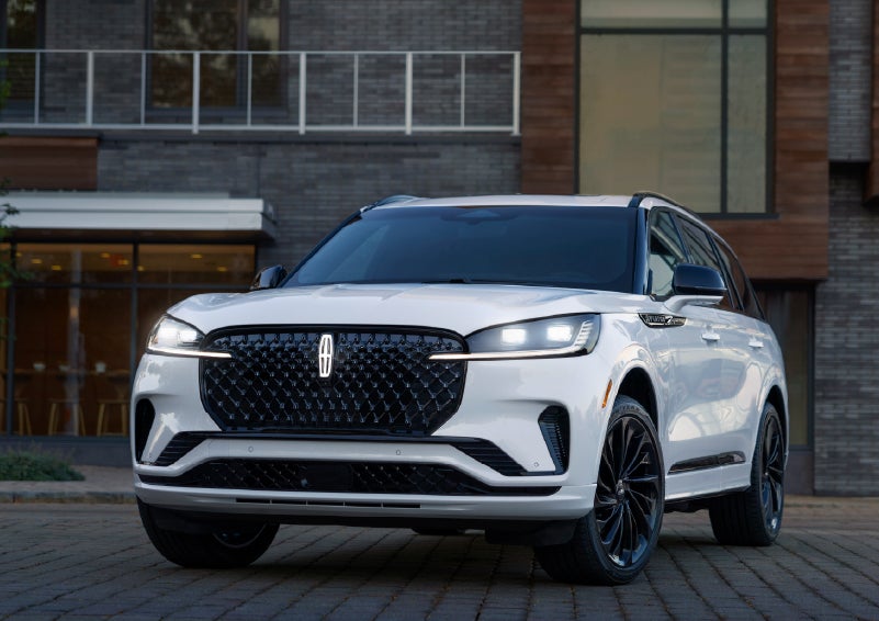 A 2026 Lincoln Aviator® Reserve model is shown with the available Jet Appearance Package parked near a restaurant. | Carman Lincoln in New Castle DE