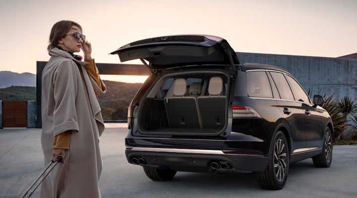 A woman approaches a 2026 Lincoln Aviator® SUV with its rear liftgate open. | Carman Lincoln in New Castle DE