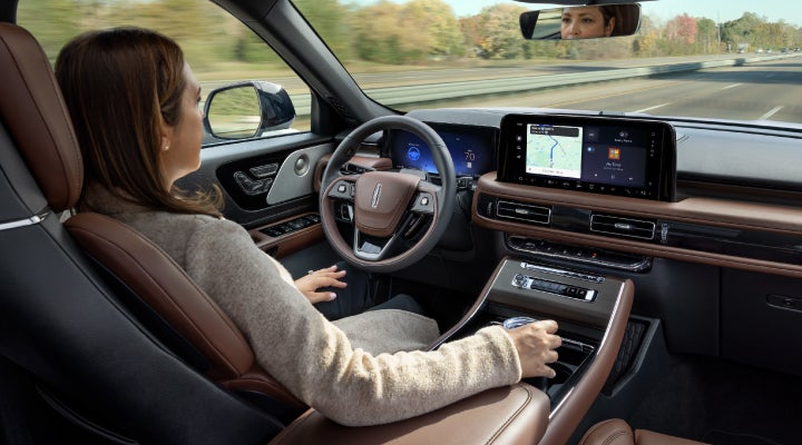A 2026 Lincoln Aviator® SUV is being driven hands-free on a highway near a forest | Carman Lincoln in New Castle DE