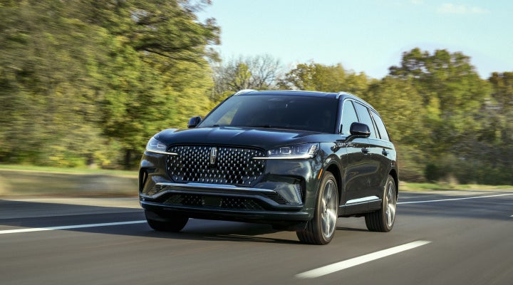 A 2026 Lincoln Black Label™ Aviator® SUV is being driven down a road lined with trees. | Carman Lincoln in New Castle DE