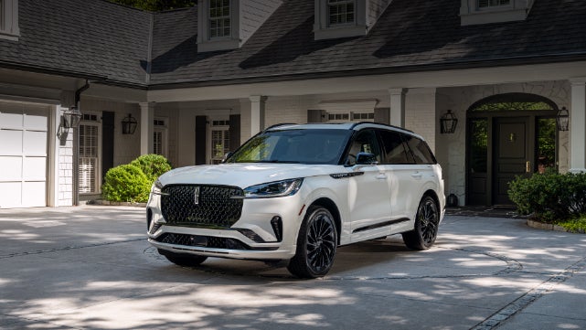 A white 2026 Lincoln Aviator® SUV is parked in the driveway of a luxury home. | Carman Lincoln in New Castle DE