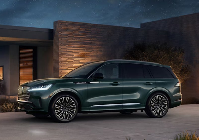 A green 2027 Lincoln Aviator® SUV is parked outside a contemporary home. | Carman Lincoln in New Castle DE