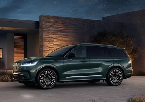 A green 2027 Lincoln Aviator® SUV is parked outside a contemporary home. | Carman Lincoln in New Castle DE
