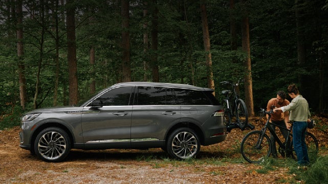 A father and son load e-bikes on a bike rack attached to a 2027 Lincoln Aviator® SUV. | Carman Lincoln in New Castle DE
