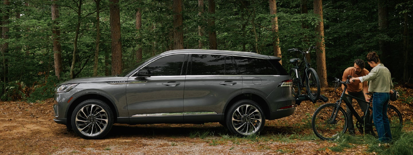 A father and son load e-bikes on a bike rack attached to a 2027 Lincoln Aviator® SUV. | Carman Lincoln in New Castle DE